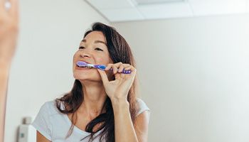 Woman brushing her teeth in bathroom