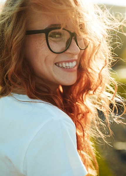 Woman with white shirt and glasses outside smiling