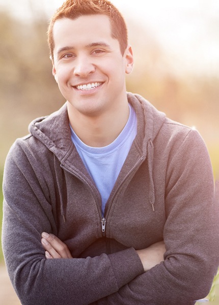 Man in a grey jacket smiling with arms folded