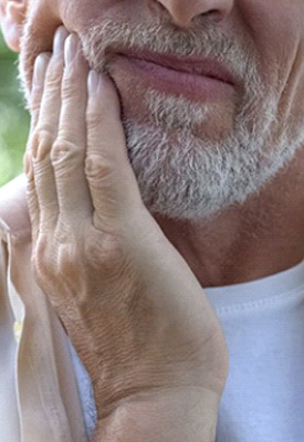 Man outdoors rubbing his jaw because of a cavity