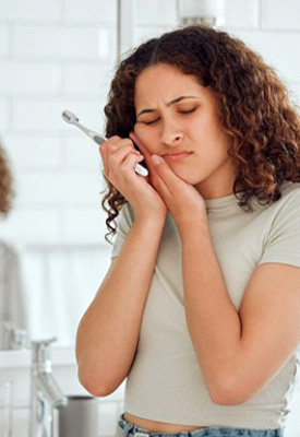 Woman holding her jaw after brushing her teeth