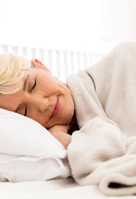 Woman sleeping peacefully in bed with warm blanket