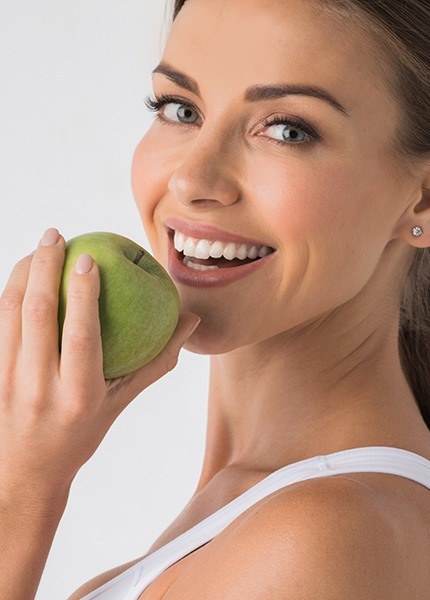 Woman eating an apple after metal free dental restoration