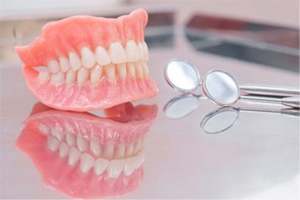 A pair of dentures sitting on a glass countertop