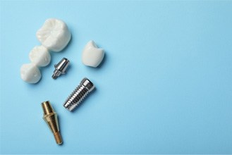 The parts of a dental implant and bridge on a light blue background