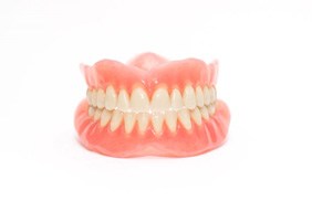 Full set of dentures against white background