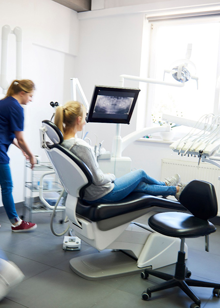 A blurred view of dentists and a woman in a dental clinic