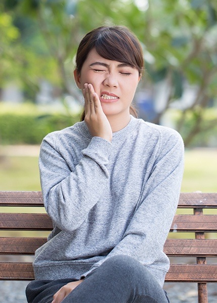 Woman in need of emergency dentistry holding jaw