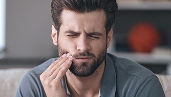 Man with toothache holding jaw