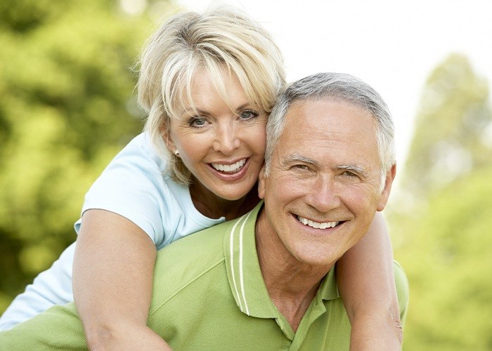 Man and woman smiling after tooth extractions