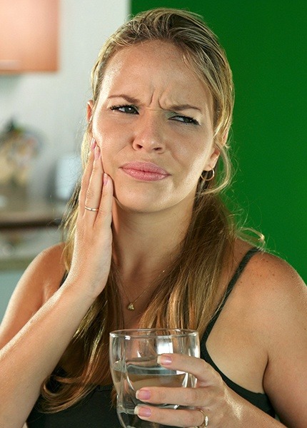 Woman in need of tooth extraction holding cheek in pain