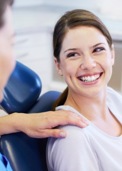 Woman in dental chair smiling at dentist