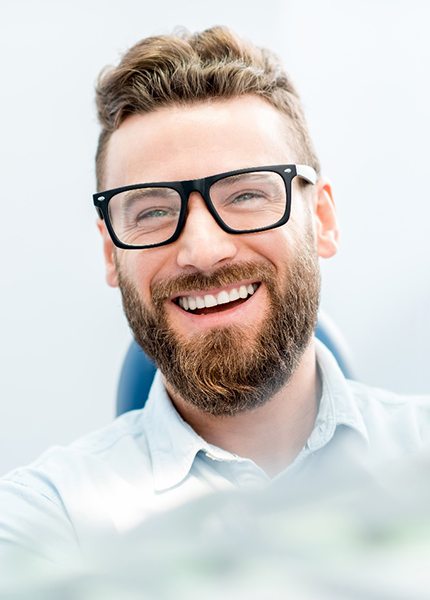 man smiling while sitting in dental chair