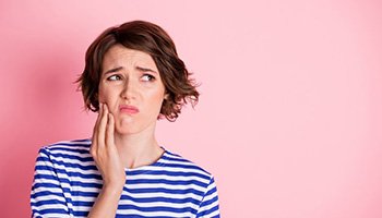 Woman holding her jaw because her gums are sore