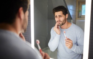 Man in  need of emergency dentistry holding jaw in pain