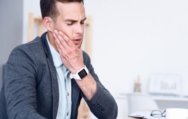 Man in need of T M J therapy holding jaw in pain