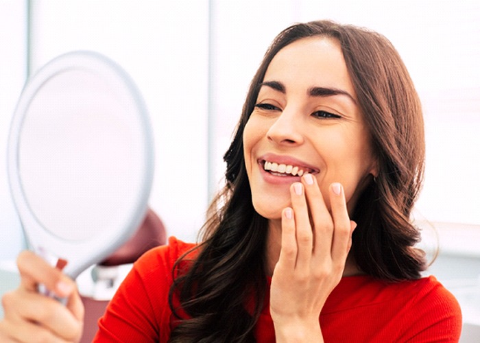 Woman looking at healthy, beautiful smile in mirror