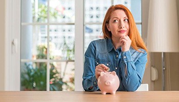 a woman putting a coin into a piggy bank