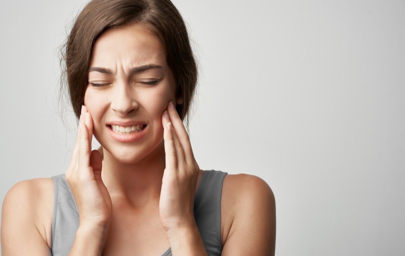 Young woman rubbing cheeks due to jaw pain