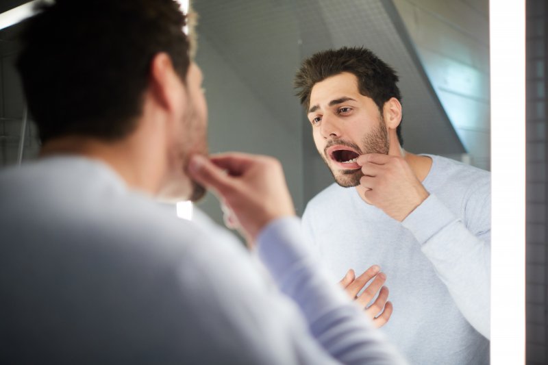 Man checking teeth in reflection