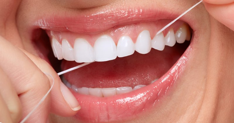 Closeup of woman smiling while flossing