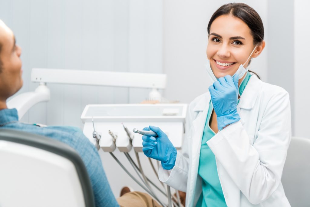 Female dentist smiling while treating patient