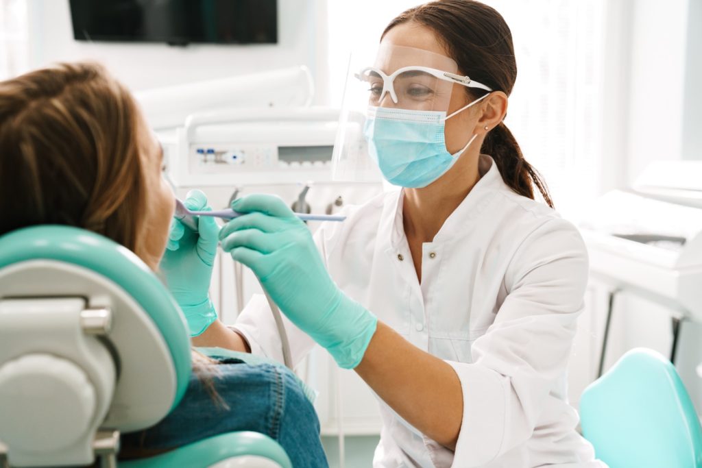 Dentist smiling while conducting oral cancer screening