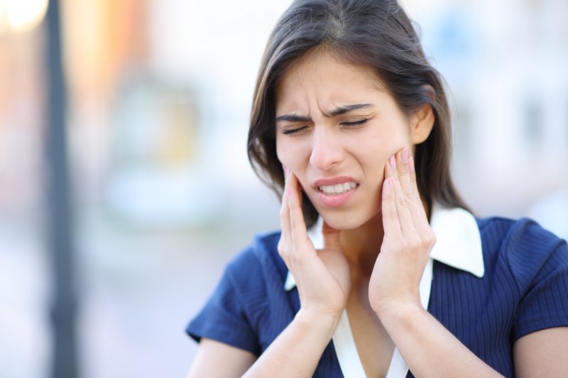 A woman rubbing her jaw due to TMD