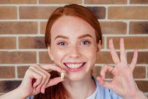 Smiling woman holding a tooth.