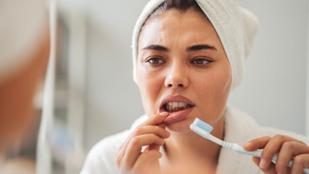 Img: A woman looking at her gums in the mirror