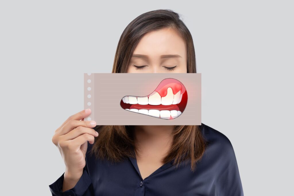 Woman with eyes closed holding picture of swollen gums in front of mouth